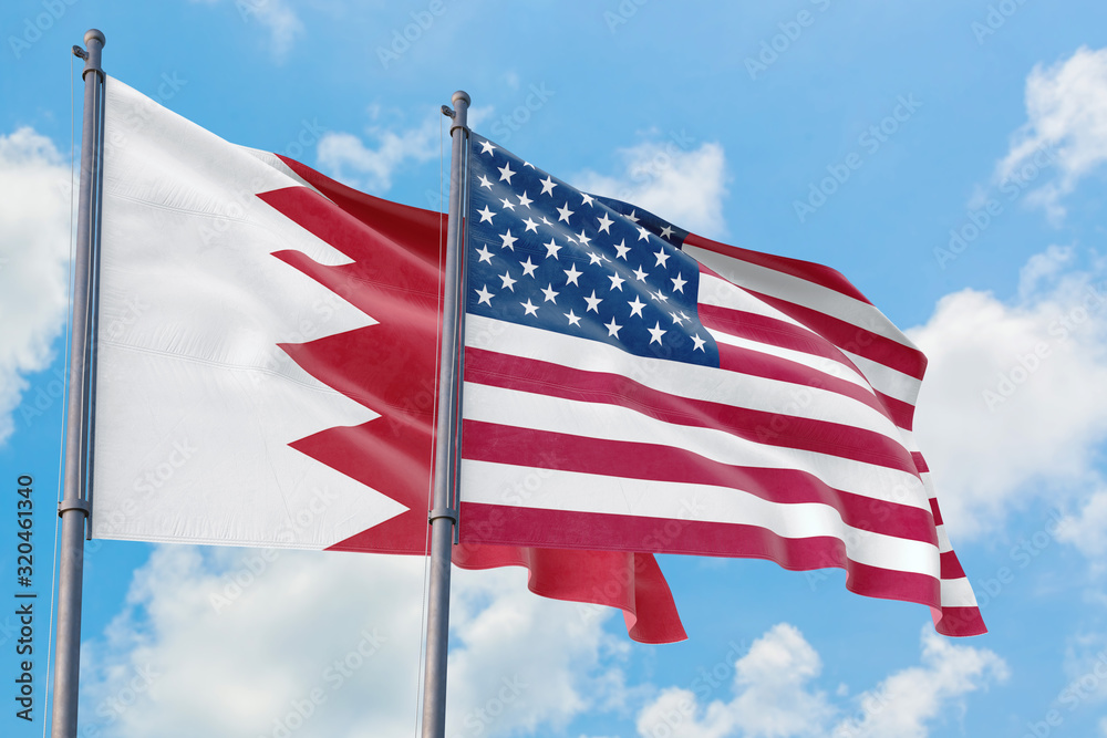 United States and Bahrain flags waving in the wind against white cloudy blue sky together. Diplomacy concept, international relations. United States and Bahrain flags waving in the wind against white cloudy blue sky together. Diplomacy concept, international relations.