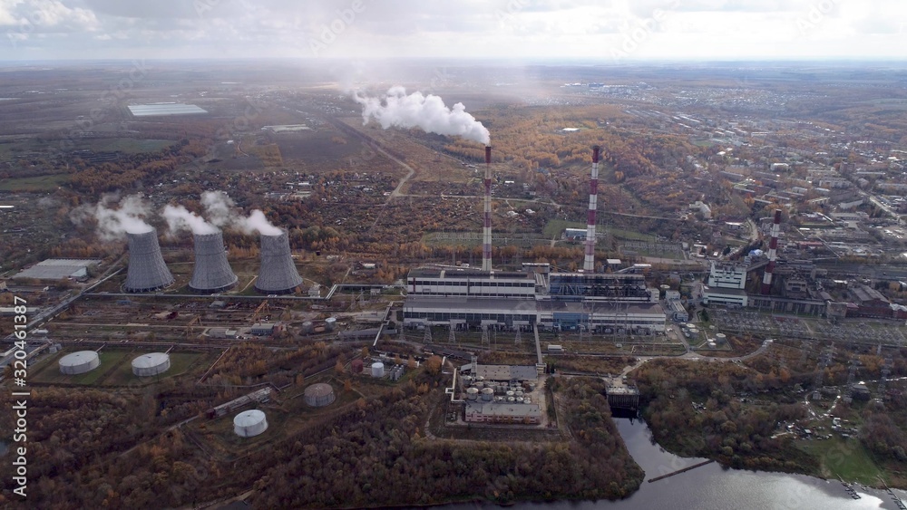 Obraz premium Power plant generating heat and electricity. High pipes and cooling towers are visible. Aerial view.