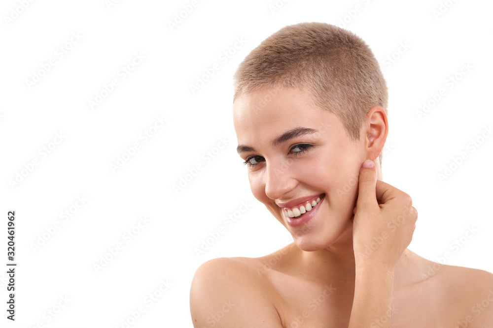 Luminous skin. Portrait of a beautiful and positive blond woman with short hair and nude make up touching her face with hand and looking at camera Luminous skin. Portrait of a beautiful and positive blond woman with short hair and nude make up touching her face with hand and looking at camera
