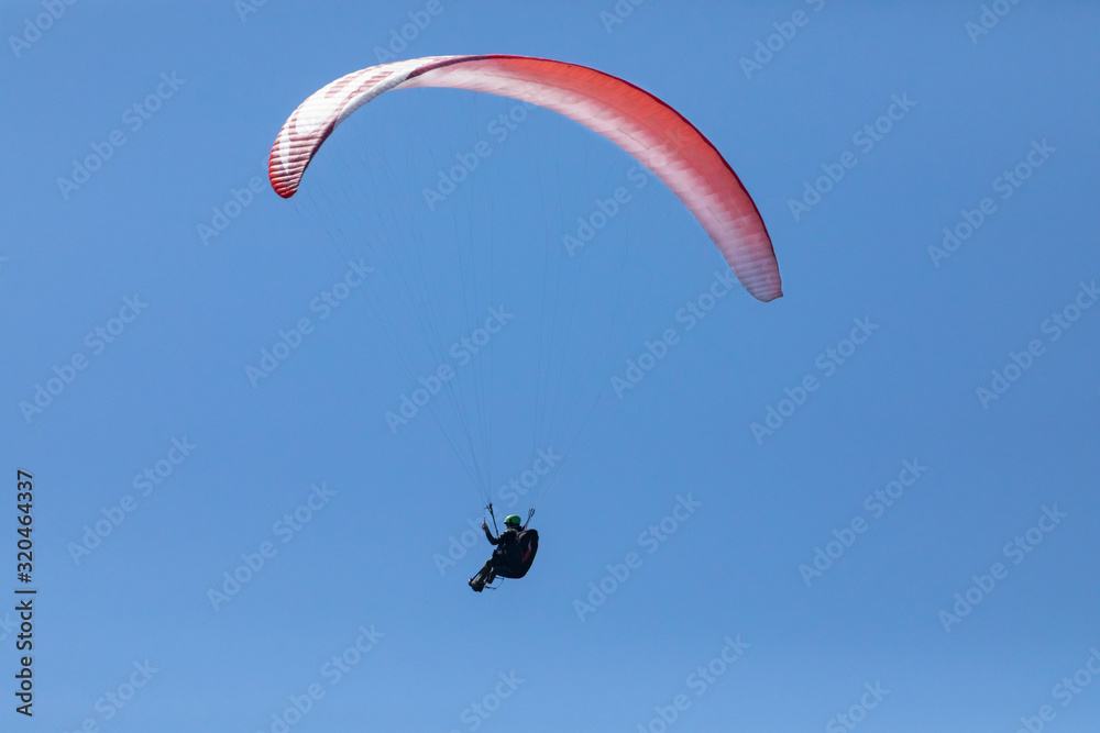 Alone paraglider flying in the clear blue sky. Paragliding in the sky on a sunny day. Long shot. Recreational and competitive adventure sport Alone paraglider flying in the clear blue sky. Paragliding in the sky on a sunny day. Long shot. Recreational and competitive adventure sport