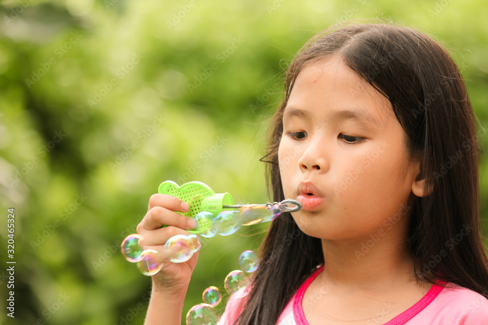 A little girl blowing soap bubbles in garden A little girl blowing soap bubbles in garden