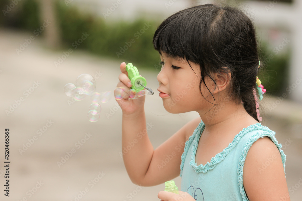 A little girl blowing soap bubbles in garden A little girl blowing soap bubbles in garden