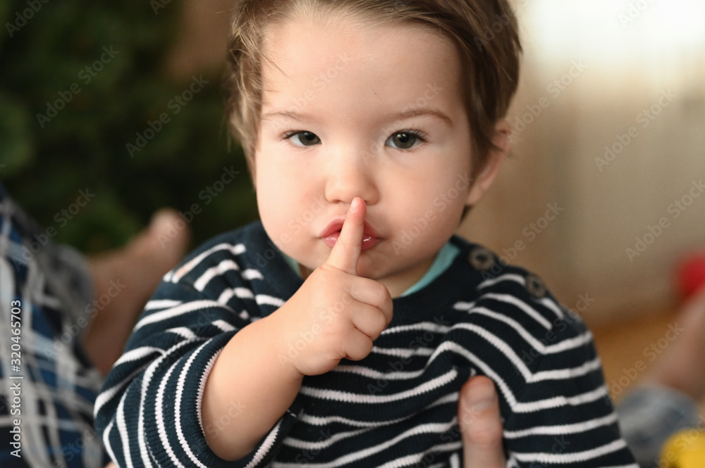 Baby and silence. shows a finger. The child is 0-1 years old. a small child shows a finger with one hand. one year old child portrait. Baby and silence. shows a finger. The child is 0-1 years old. a small child shows a finger with one hand. one year old child portrait.