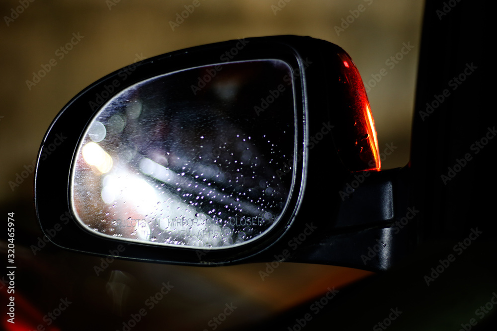 Car side-mirror with raindrops and reflection at night while driving Car side-mirror with raindrops and reflection at night while driving