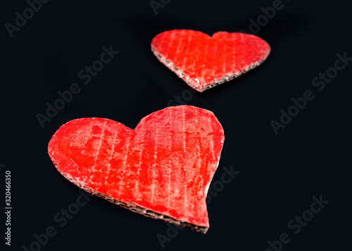 Two red heart-shaped recycled cardboard on dark background. Love symbol for valentines day. Concepts of Love and Romance.