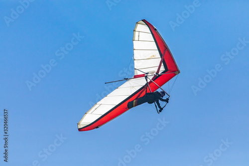 Hang glider flying overhead. Clear sunny day. Recreational activities during the summer holidays. Soaring flight of hang gliding