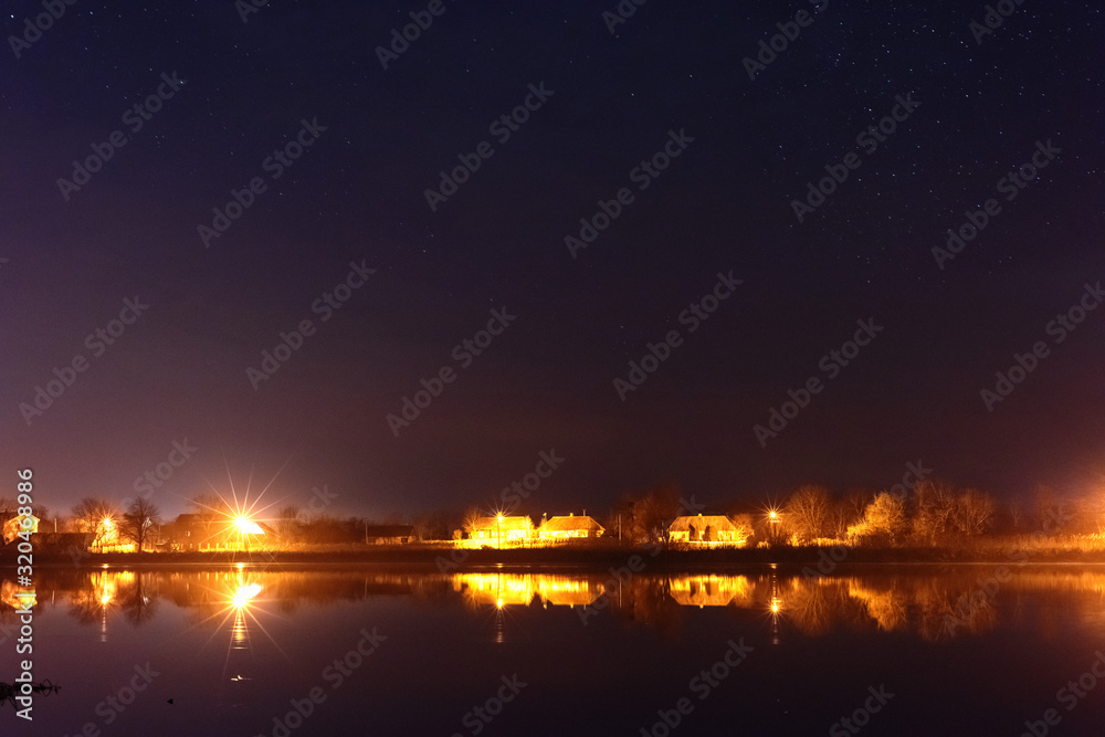 A magical starry night on the river bank with a large tree and a milky way in the sky and falling stars A magical starry night on the river bank with a large tree and a milky way in the sky and falling stars