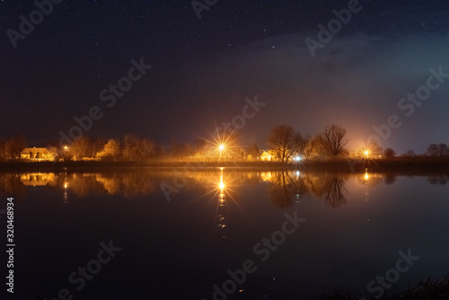 A magical starry night on the river bank with a large tree and a milky way in the sky and falling stars © reme80