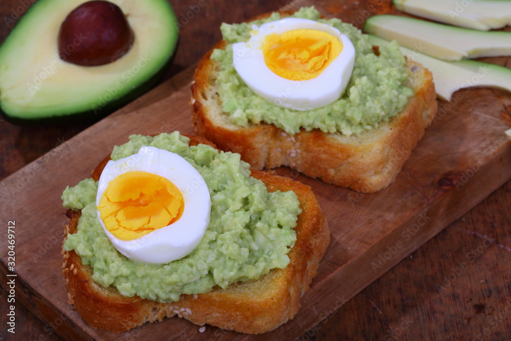 Sandwich with avocado and egg on a wooden table
