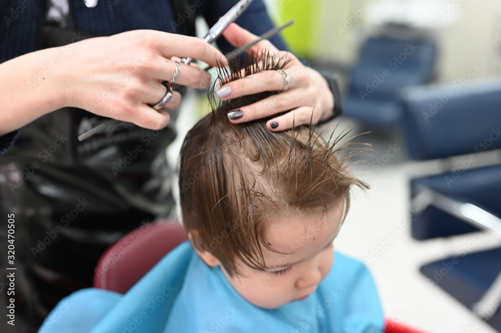 A child at the hairdresser. The first haircut of the child at the hairdresser. Baby haircut toddler. A child at the hairdresser. The first haircut of the child at the hairdresser. Baby haircut toddler.