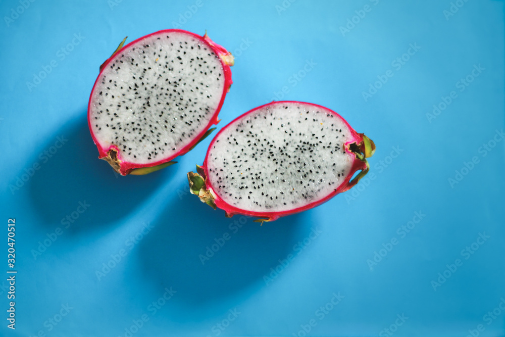 Fresh sliced dragonfruit or pitaya against a bright blue background to show color contrast, concept of fun, summer and pop culture Fresh sliced dragonfruit or pitaya against a bright blue background to show color contrast, concept of fun, summer and pop culture