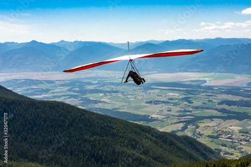 Long shot of flying extremal hang glider. Young man enjoying his recreational journey to Creston, British Columbia, Canada photo