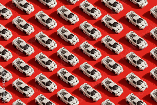 Фотография pattern of white toy car model Ferrari on red background