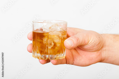 Man's hand holding a glass of whiskey on a white background