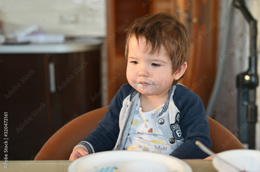 The dirty face of a young child with food. Babys face in white liquid. Close-up. The dirty face of a young child with food. Babys face in white liquid. Close-up.