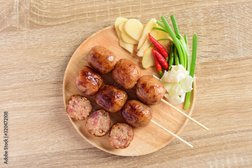 Thai sausage or Isan sausage (grilled fermented rice with pork) eating with fresh ginger, cabbage and chili peppers