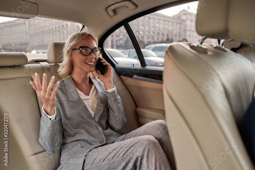 We did it. Excited businesswoman in classic wear sitting in the car and talking by the phone with her business partner © Svitlana