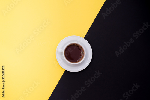 cup of fresh espresso on yellow and black background, top view with a copy space