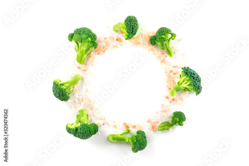 Broccoli florets, shot from the top on a white background, with Himalayan salt, forming a frame for copy space