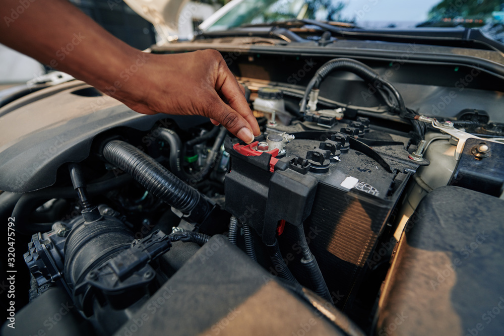 Close-up image of woman checking or changing car battery Close-up image of woman checking or changing car battery