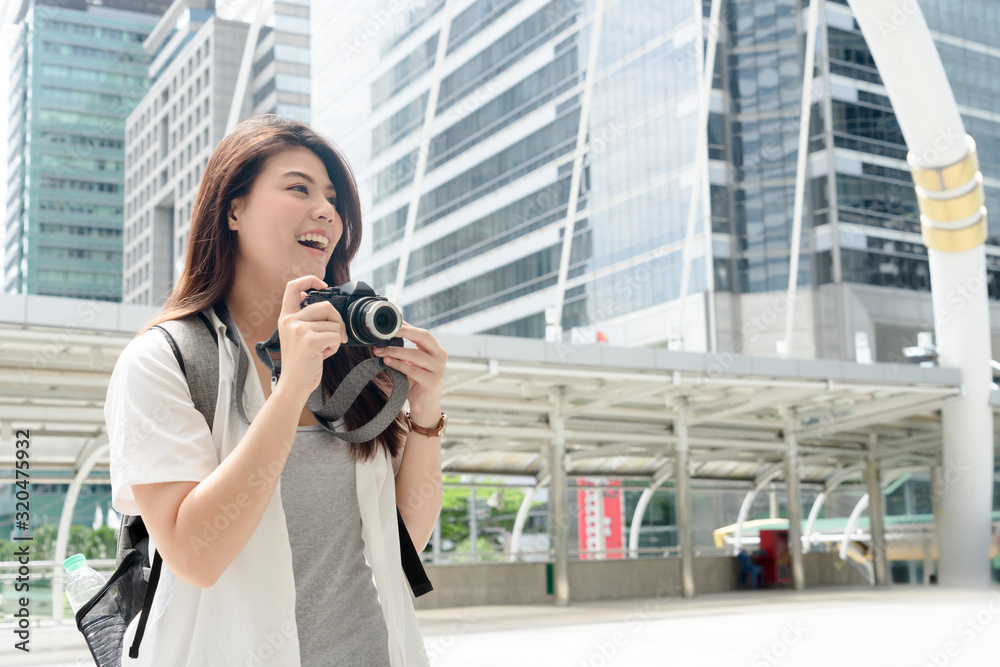 Traveler pretty blissful positive girl holding photo camera while walking around the city