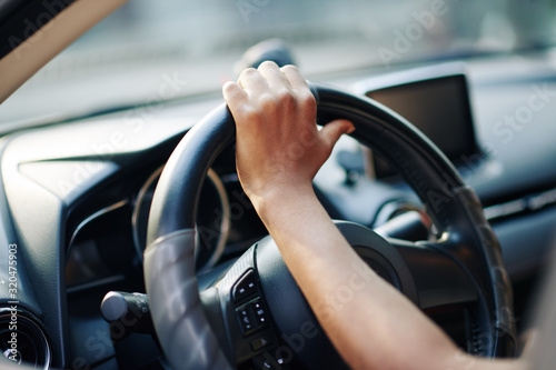 Hand of woman on steering wheel of her new car © DragonImages