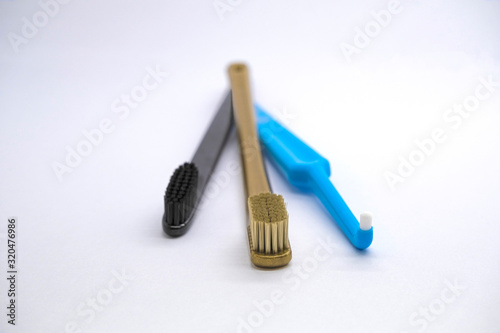 Three colored  toothbrushes gold  black and blue for different purposes on a light background