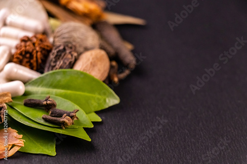 Extreme close up of cloves and green leaves with blurred capsules in the black background. Herbal concept photo