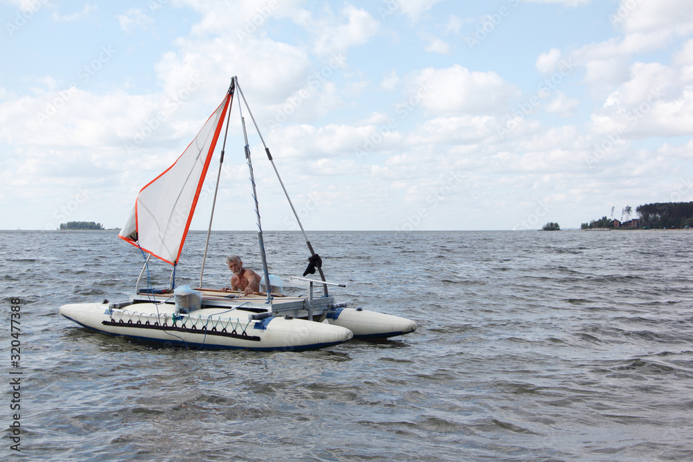Naklejka premium Man lowering catamaran into river, Ob Reservoir, Novosibirsk, Russia