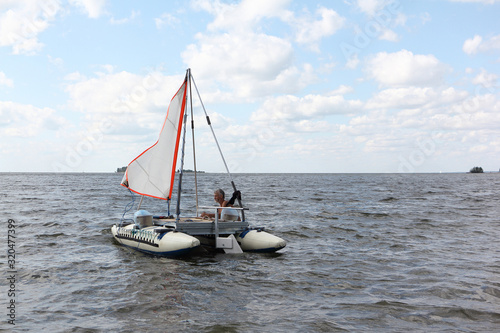 Man lowering catamaran into river, Ob Reservoir, Novosibirsk, Russia photo