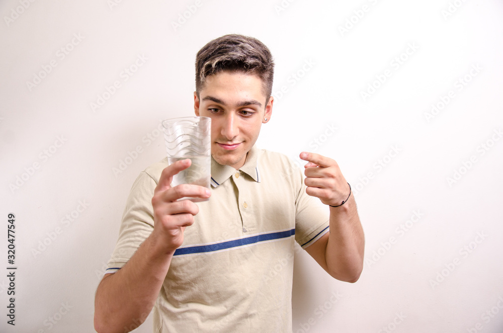 Young man showing a glass of water 