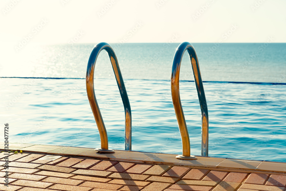 Stainless steel laddder in a swimming pool in a resort hotel Stainless steel laddder in a swimming pool in a resort hotel