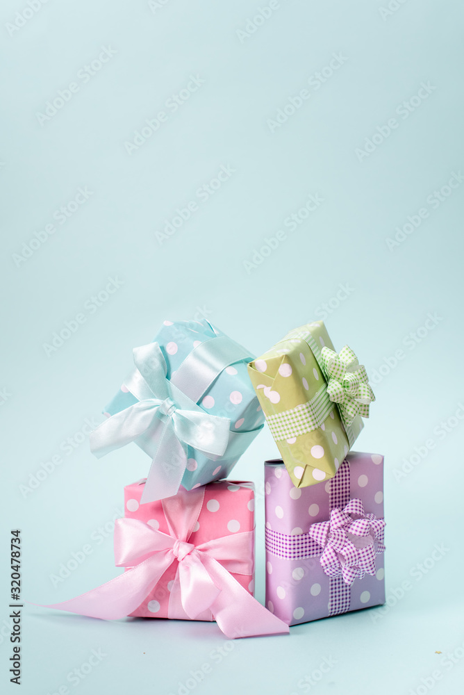 Holiday flat lay with gift boxes wrapped in colorful paper and tied with bows on blue background, decorated with confetti. Birthday, Christmas and sale concept, top view. Holiday flat lay with gift boxes wrapped in colorful paper and tied with bows on blue background, decorated with confetti. Birthday, Christmas and sale concept, top view.