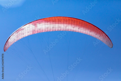 Paragliding sport. Close-up view of paragliding parachute against the blue sky. Colorful parachute of flying Paraglider pilot