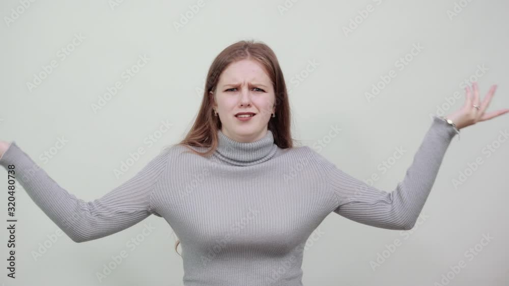 A young beautiful woman on the background raises her hands in sign that she does not know anything does not understand A young beautiful woman on the background raises her hands in sign that she does not know anything does not understand