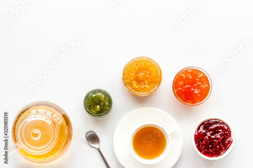 Fruit jam near tea on white kitchen desk copy space