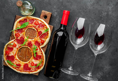 Dinner for two. Pizza in the form of 8, a bottle of wine and glasses for International Women's Day on March 8 on a stone background. March 8 celebration concept.