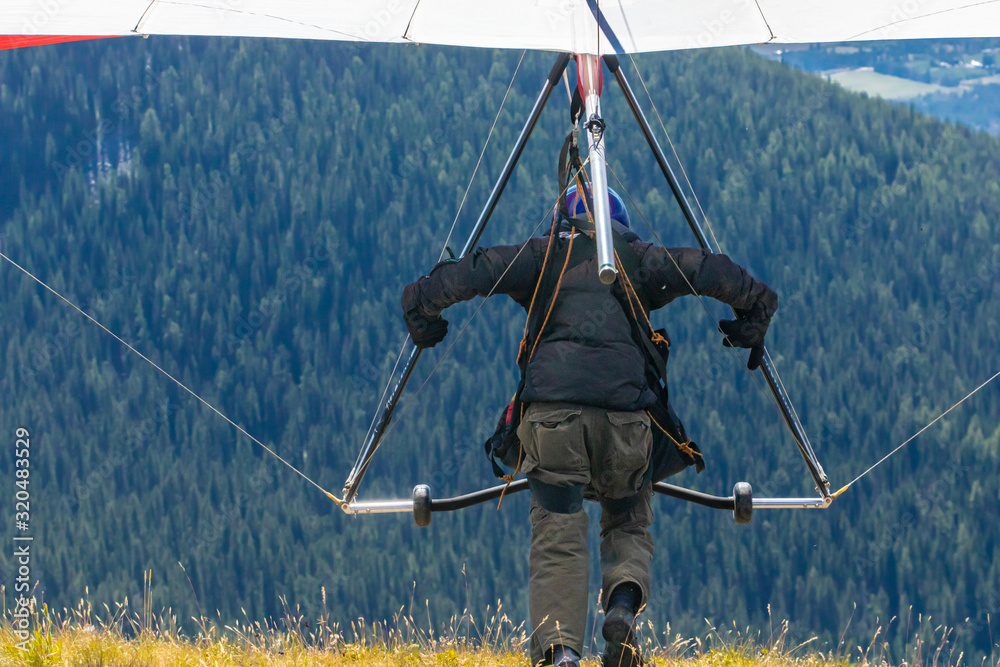 Back view of professional Hang glider man running and taking off. Hang