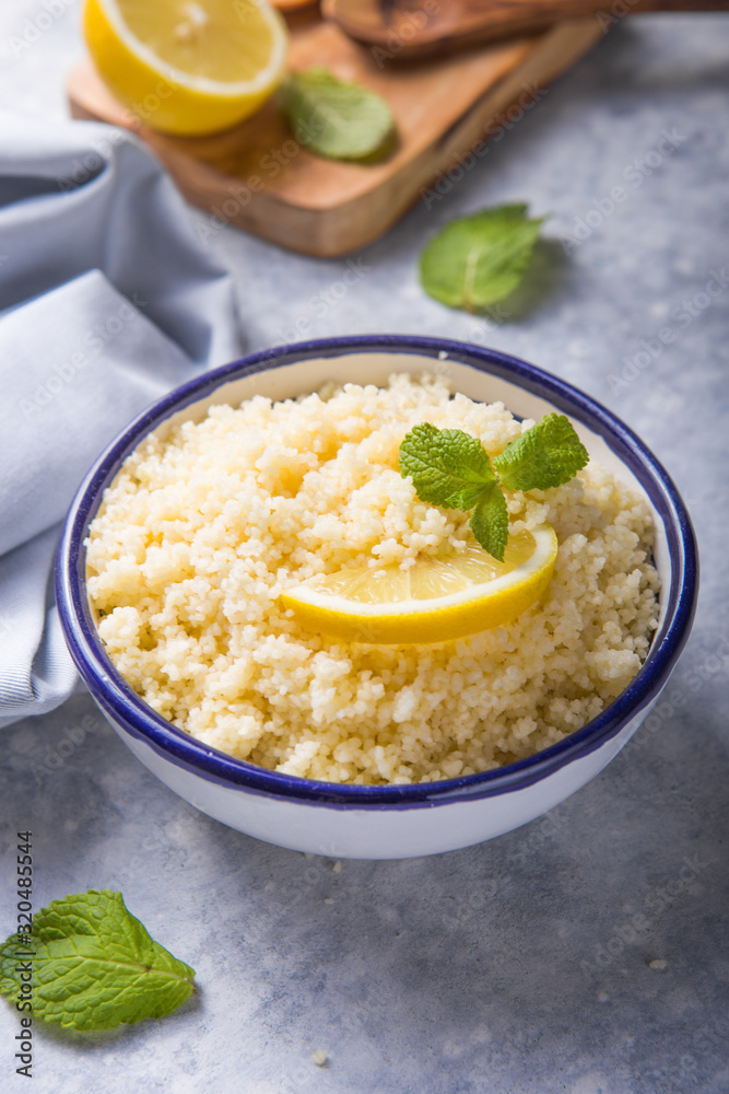 Couscous with mint and lemon in plate on dark rustic table from above. Copy space for text. Flat lay. Couscous with mint and lemon in plate on dark rustic table from above. Copy space for text. Flat lay.