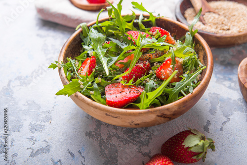 Diet menu concept. Summer Healthy salad with quinoa, strawberry, and arugula. Top view flat lay background on light stone table with copy space.