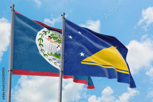 Tokelau and Belize flags waving in the wind against white cloudy blue sky together. Diplomacy concept, international relations.