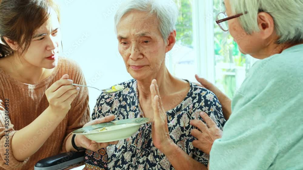 Unhappy asian senior woman rejecting,gesture hand “NO” elderly patient bored with food or boredom,old people getting sick and tired of food in wheelchair at home,loss of appetite,anorexia concept