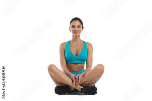 Slender athletic woman in beautiful comfortable turquoise sportswear sitting Isolated on a white background.