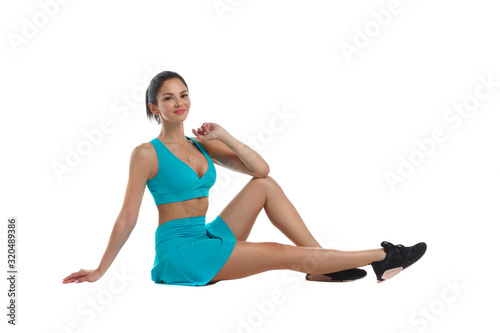 Slender athletic woman in beautiful comfortable turquoise sportswear sitting Isolated on a white background.