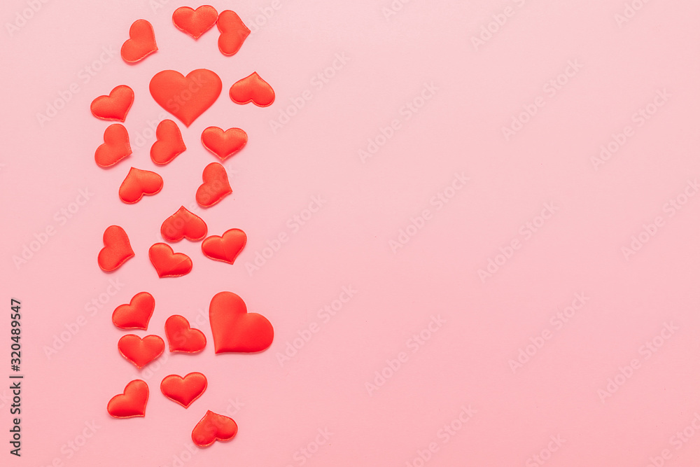 Red hearts symbol of love scattered on pink background. Valentine's day concept. Horizontal frame copy space.
