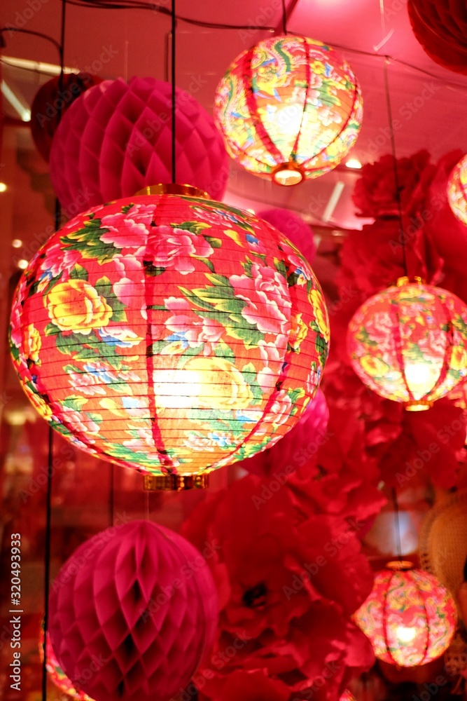 In selective focus a row of beautiful Chinese lanterns hanging on a wire with red background 