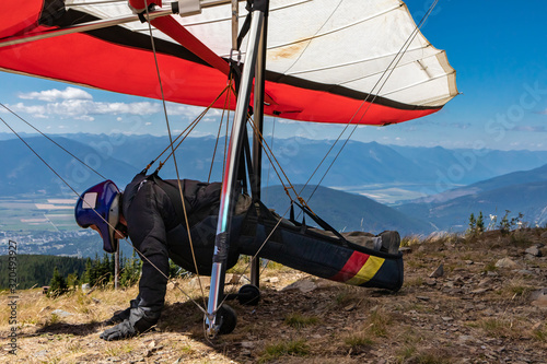 Man with hang-glider getting ready to fly from the top of mountain hill. Para glider pilot getting ready to launch. Side view