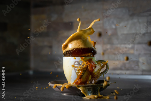 Splash of coffe in a cup. Blurred dark background. Movement and action