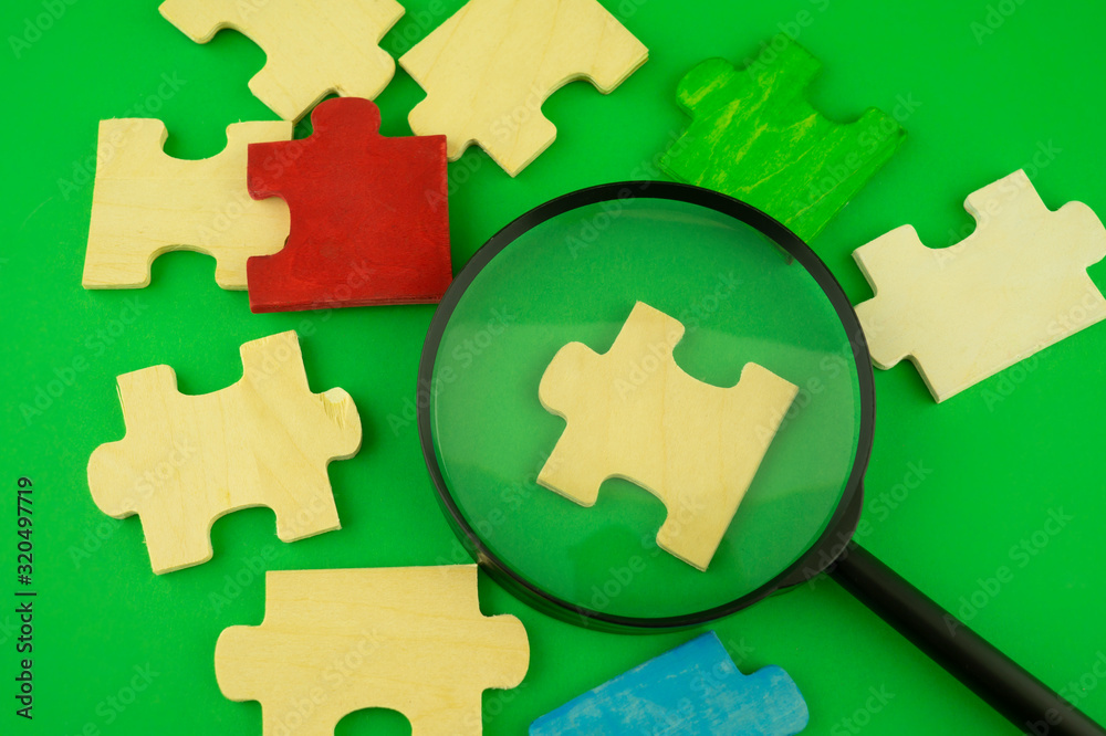Fototapeta premium Jigsaw puzzle pieces with magnifying glass