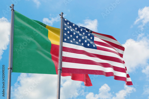 United States and Benin flags waving in the wind against white cloudy blue sky together. Diplomacy concept  international relations.